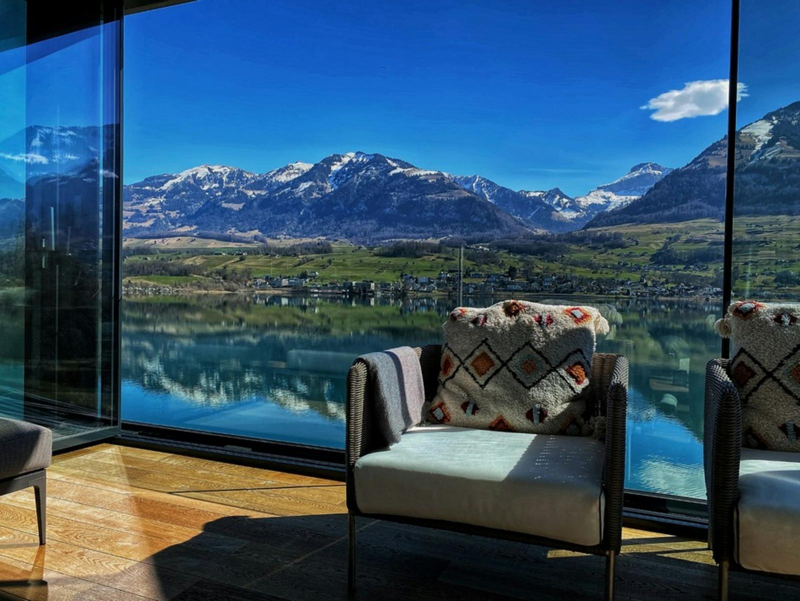 Intérieur contemporain face à un lac suisse et aux montagnes enneigées